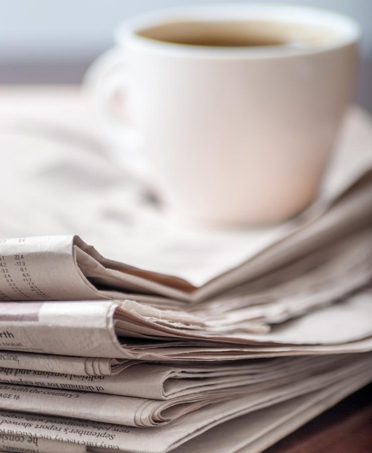 Kaffeetasse, die auf einem Zeitungsstapel steht