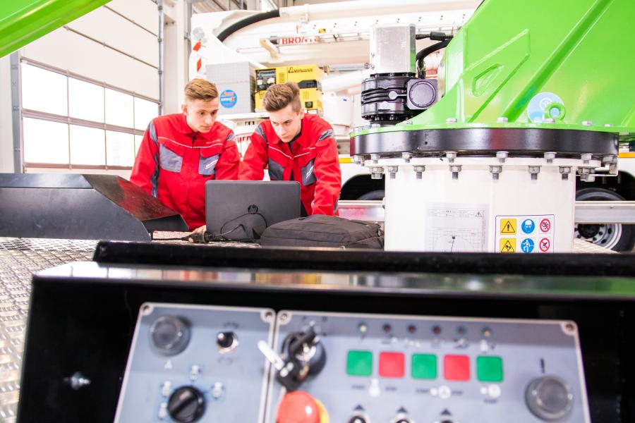 Working people in front of a laptop in a factory hall